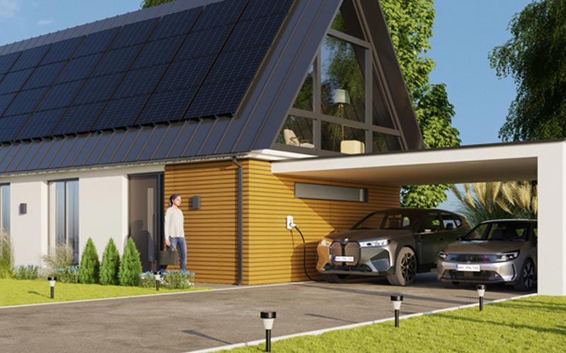 Ein modernes Haus mit Solardach, Carport und zwei Autos. Vor dem Haus stehen drei Personen, zwei Kinder sitzen auf dem Rasen.